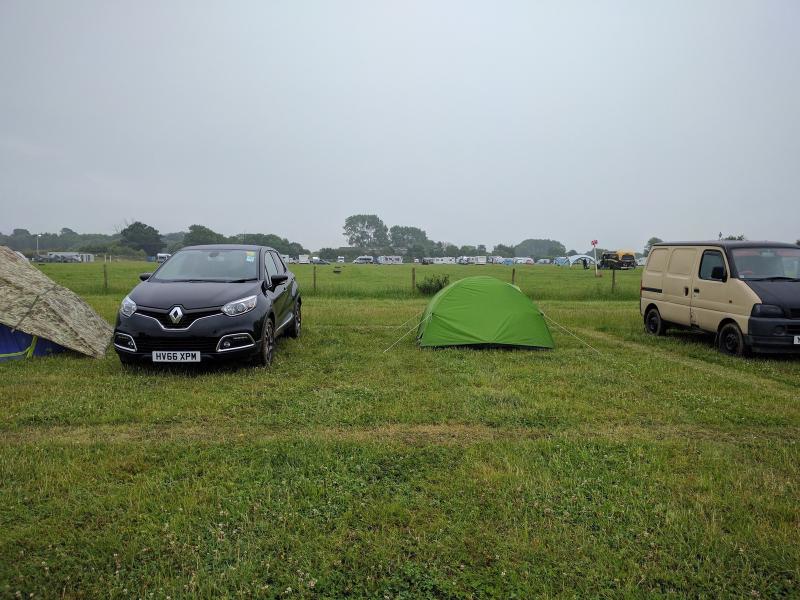 Small tent pitched beside a rental car at Goodwood